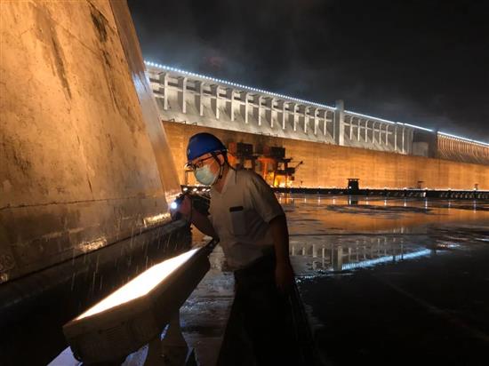 汛期内，长江电力三峡电厂巡检人员在夜雨中检查。